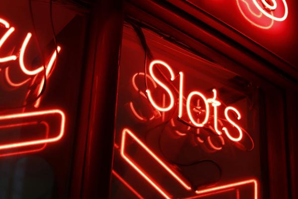 Un panneau rouge indiquant « Slots » dans l’obscurité.