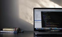 Un bureau avec ordinateur ouvert et quelques livres