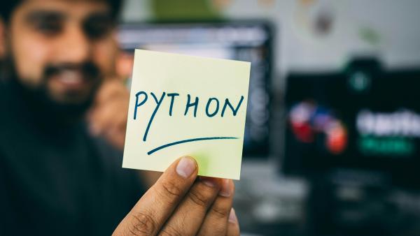 Une personne tenant un post-it avec “Python” écrit dessus